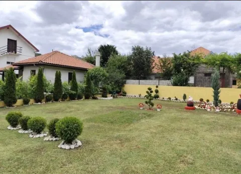 Lijepo uređeno dvorište sa travnjakom, ukrasnim rastinjem i pogledom na kuću. - image 2