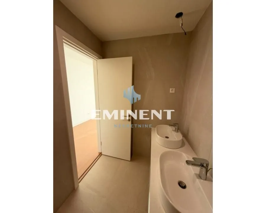 Bathroom with two washbasins and a view of the hallway through the open door.
