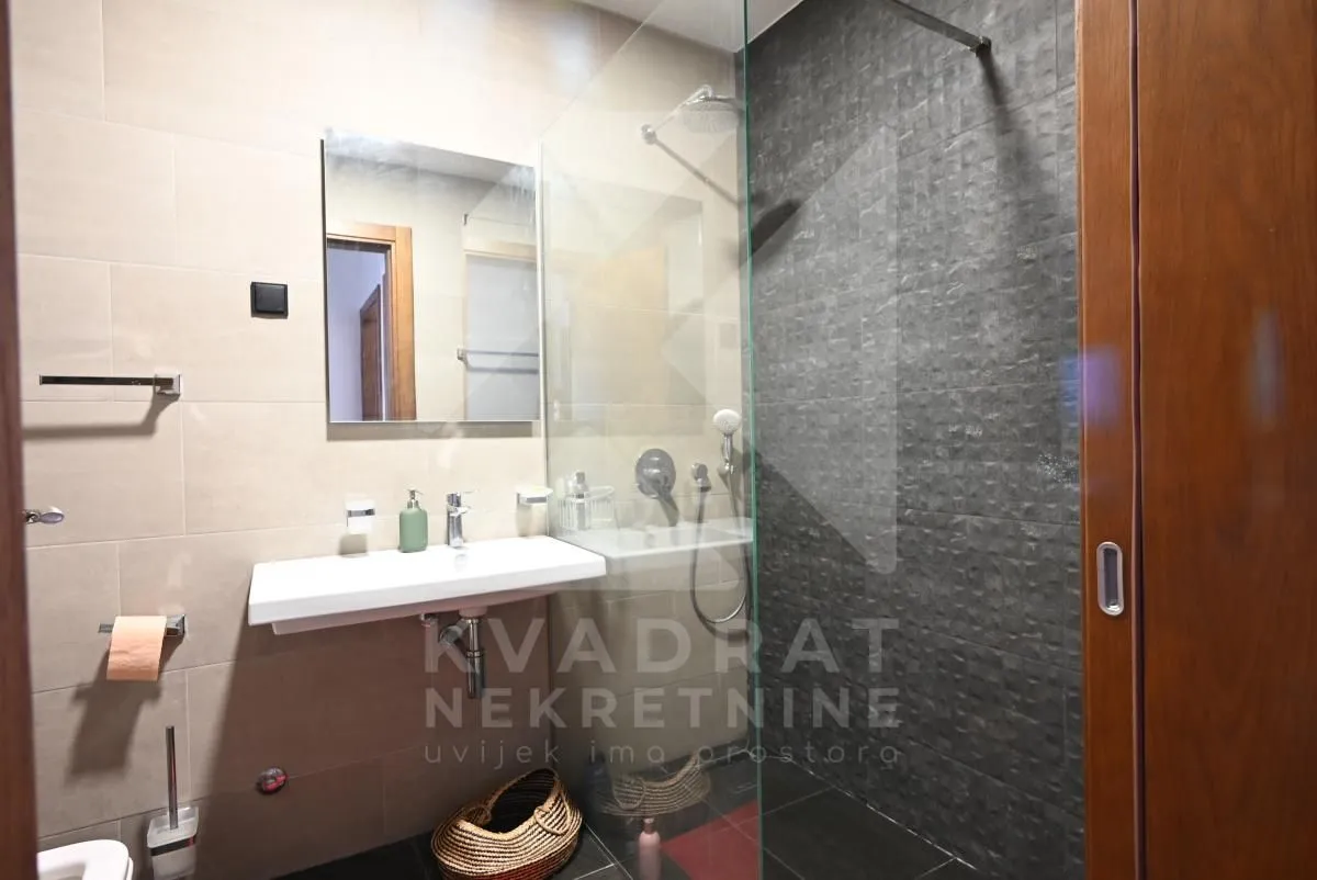 Modern bathroom with a walk-in shower, washbasin, and mirror.