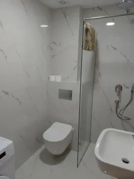 Modern bathroom with marble-patterned tiles and a walk-in shower. - image 13