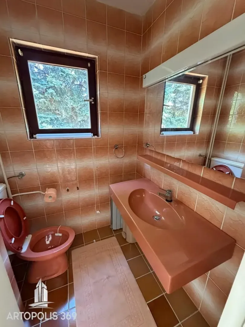 Kupatilo obloženo keramičkim pločicama sa prozorom.