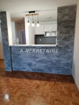 Dnevni boravak sa pogledom na kuhinju kroz šank obložen dekorativnim kamenom. - image 5