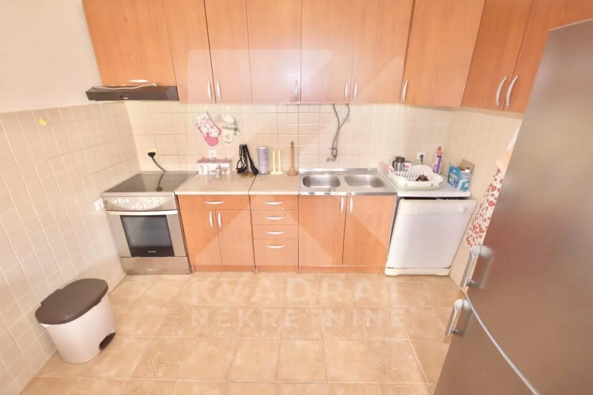 Kitchen with wooden cabinetry, stove, and sink.