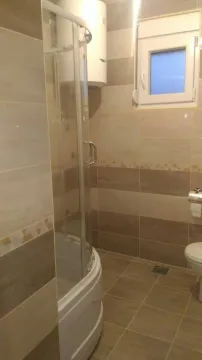 A simple bathroom with a shower cabin, boiler, and light tiles. - image 8