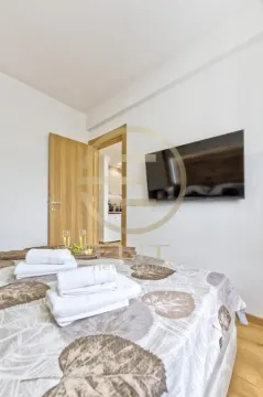 Nameštena spavaća soba sa bračnim krevetom, televizorom na zidu i pogledom prema prolazu. - image 9