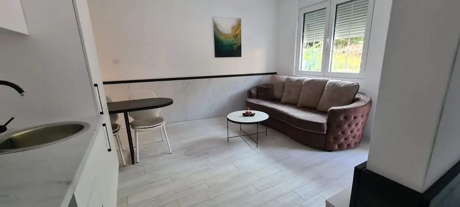 Living room with sofa, dining table, and kitchen units in the corner.