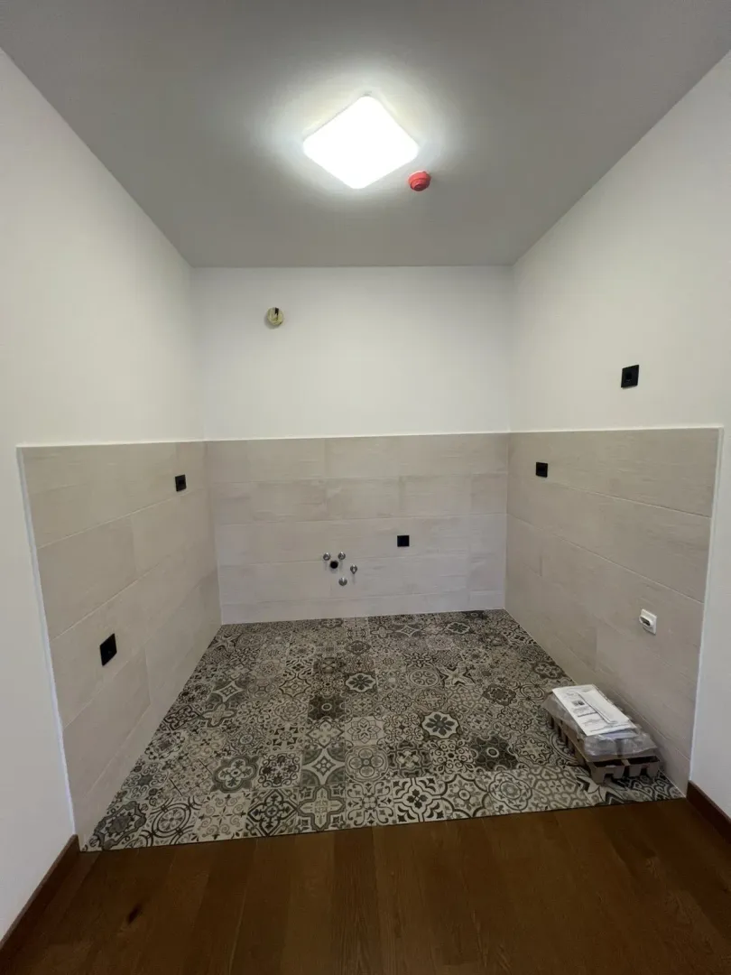 An unfinished empty space featuring decorative floor tiles.