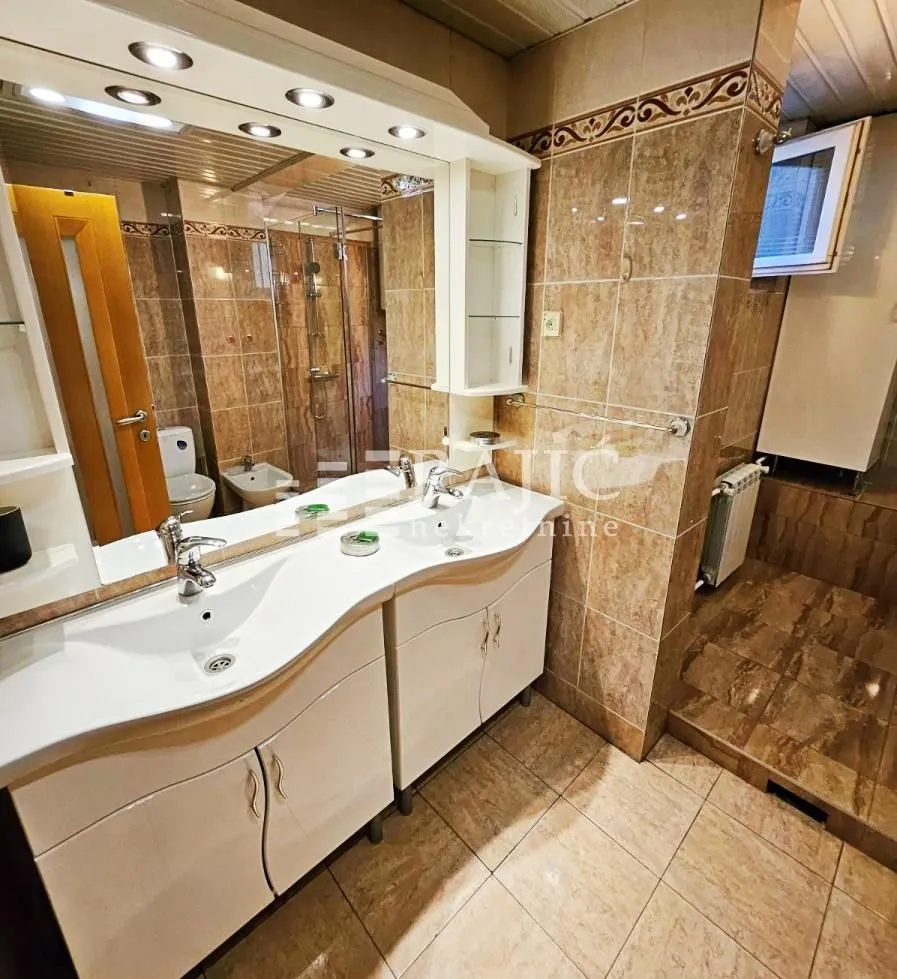 Tiled bathroom featuring a double vanity and a large mirror.