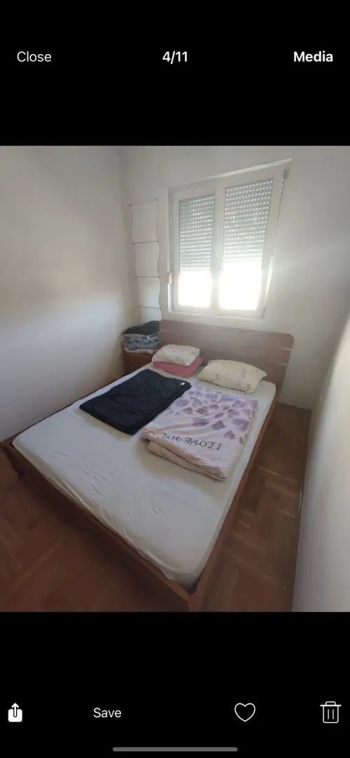 A simple bedroom with a wooden double bed and a window.