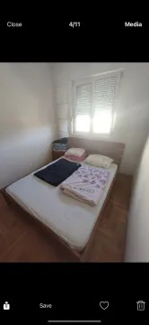 A simple bedroom with a wooden double bed and a window. - image 7