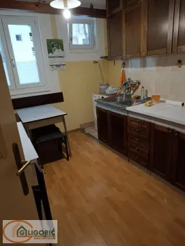 Older kitchen with wooden cabinets and a small dining table. - image 9
