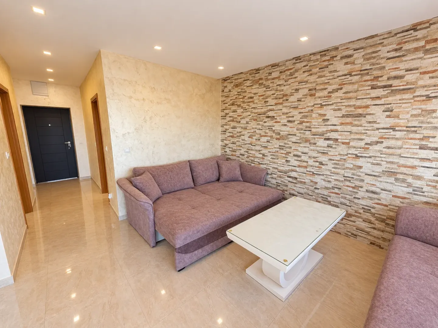 Living room with a sofa and a decorative stone wall.