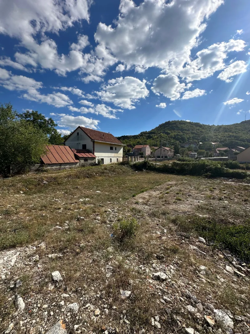 Pogled na plac i kuću sa okućnicom u seoskom okruženju.