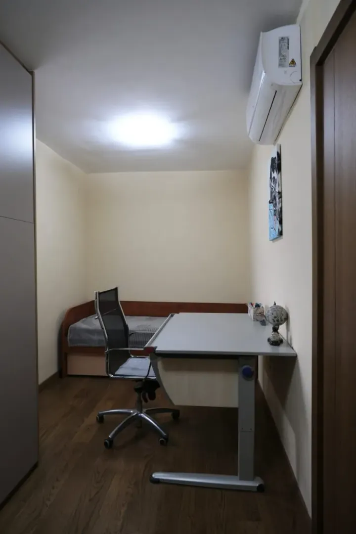 A small bedroom with a study desk and a single bed.