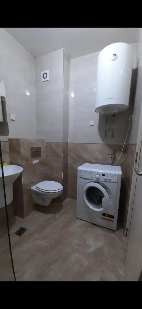Jednostavno kupatilo sa toaletom, veš mašinom i bojlerom.