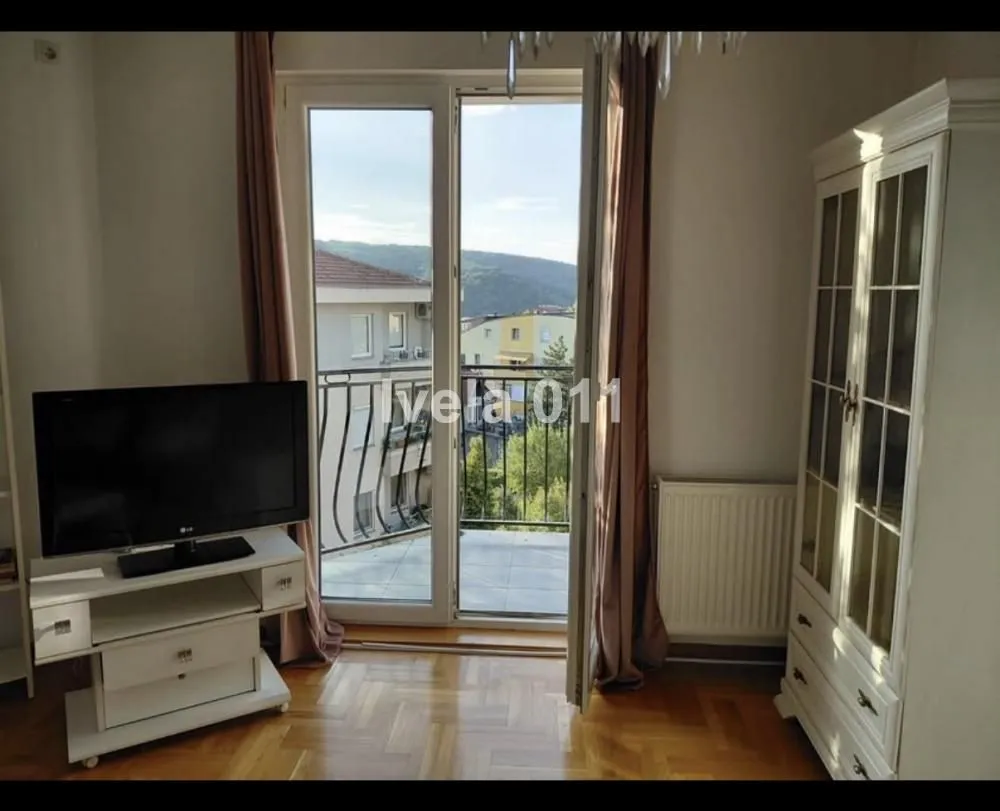 Dnevna soba sa izlazom na balkon i pogledom na okolinu.
