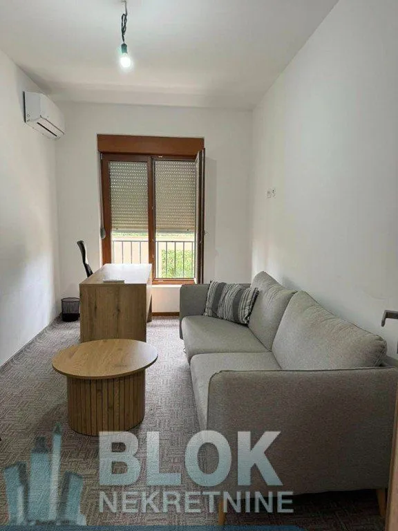 Living room with a gray sofa, coffee table, and a desk by the window.
