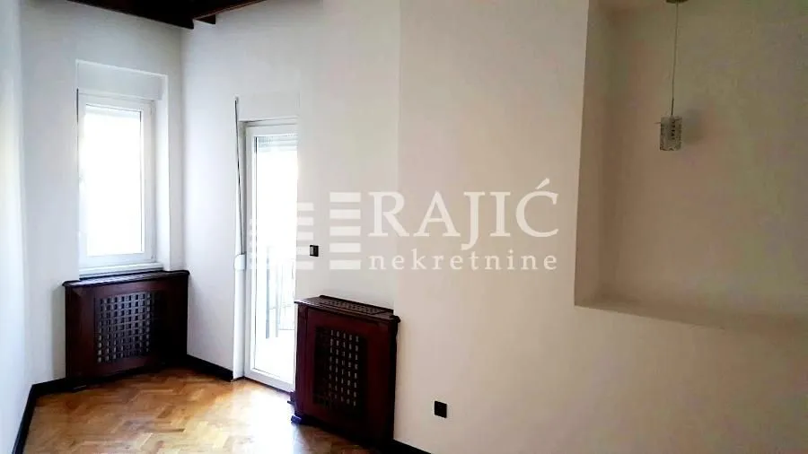 Empty room with parquet flooring, a window, and a door leading to the terrace.