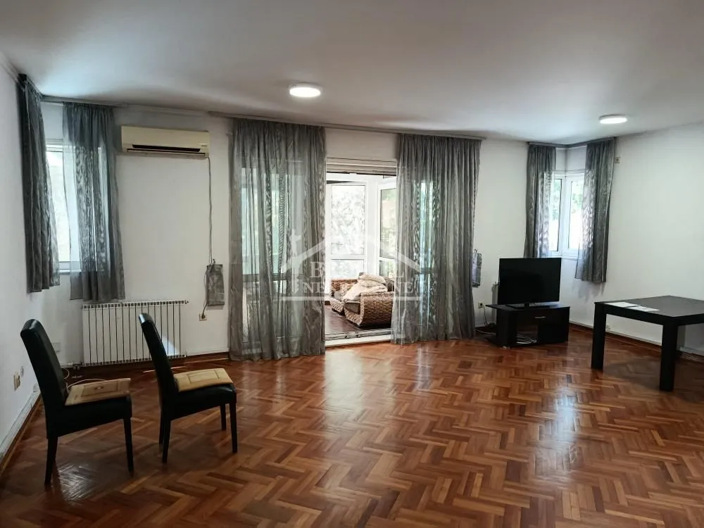Spacious living room with wooden parquet flooring, a TV, and access to the terrace.