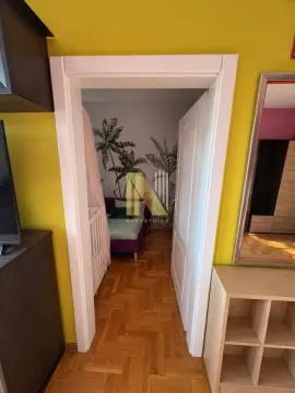 Pogled iz hodnika na spavaću sobu sa krevetom i tapetama sa motivom palmi. - image 5