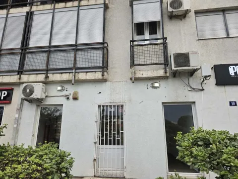 Part of a residential-commercial building facade showing an entrance door and windows. - image 5