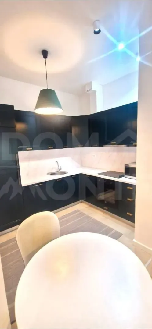Modern kitchen with dark elements and a dining table in the foreground.