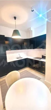 Modern kitchen with dark elements and a dining table in the foreground. - image 8