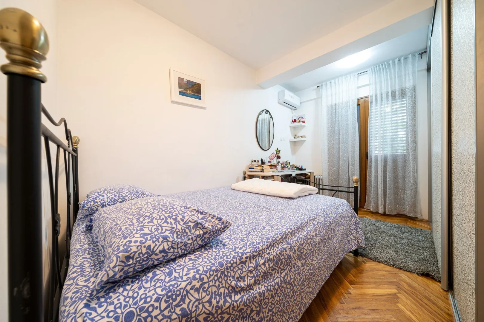 Bright bedroom with a double bed and wooden flooring.