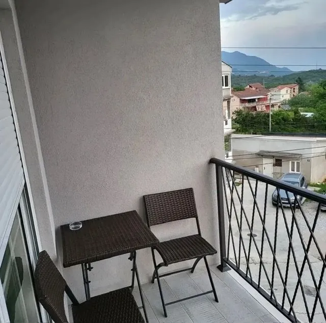 Small covered balcony space with a table and chairs and a view of the surroundings.