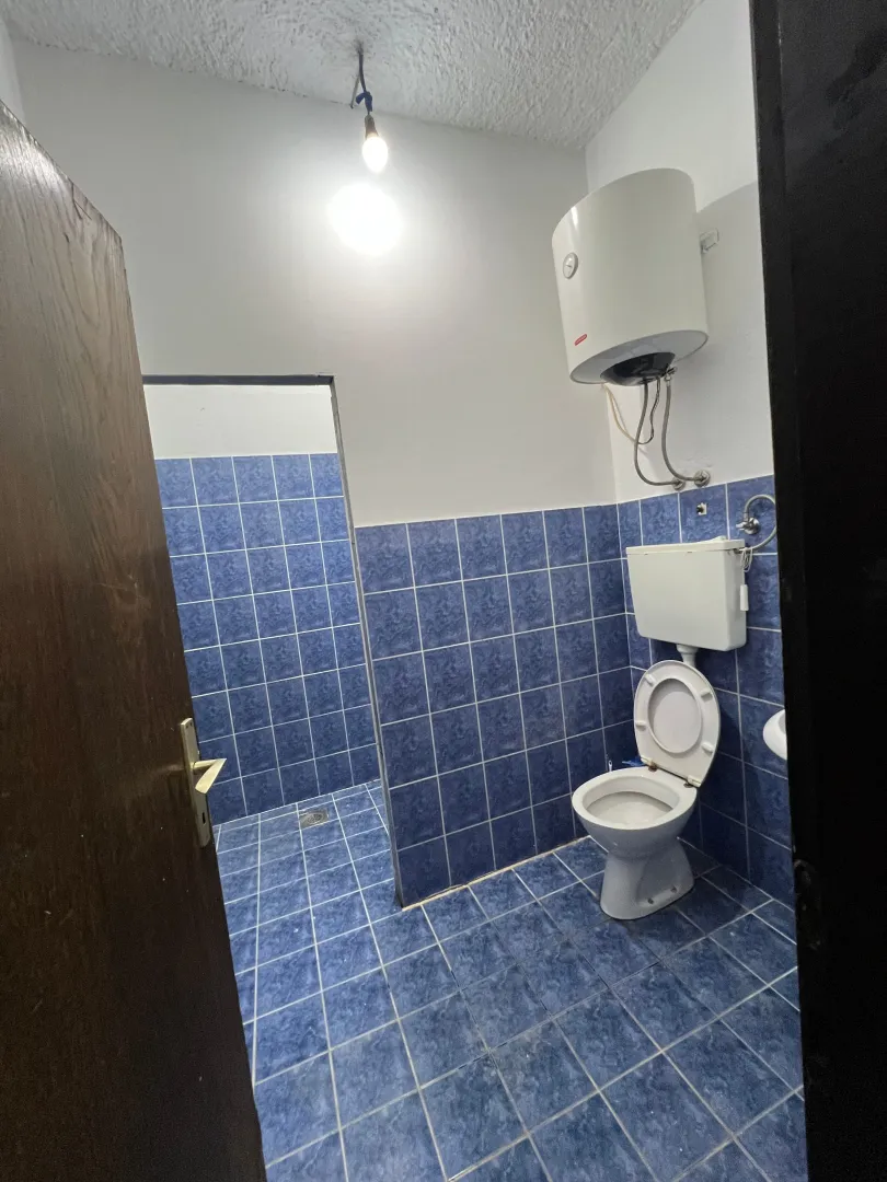 Small bathroom with blue tiles, toilet, and water heater.