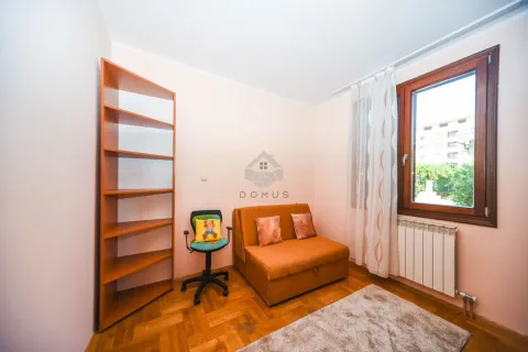 Smaller room with a pull-out sofa, office chair, and wooden shelving unit. - image 11