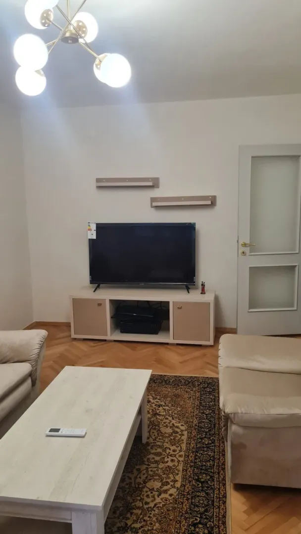 Dnevna soba sa garniturom za sjedenje, klub stolom i televizorom na komodi.
