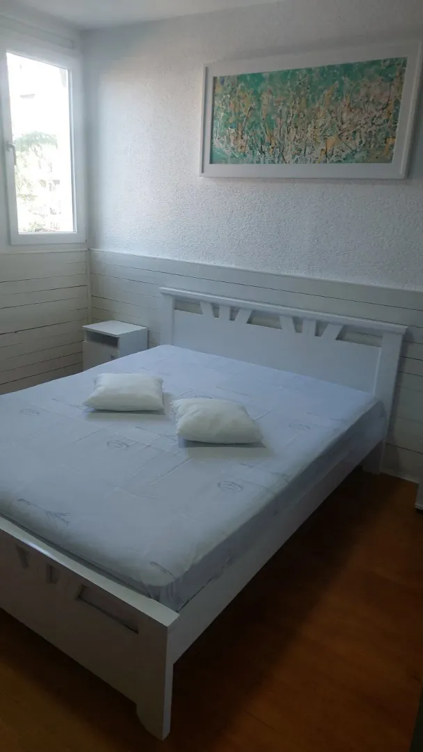 Svijetla spavaća soba sa bijelim drvenim krevetom.