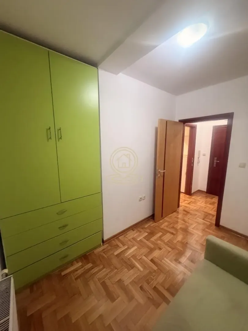 Small room with a green wardrobe, parquet flooring and an open door.