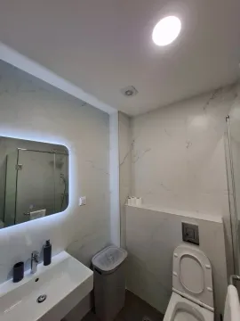 Modernly equipped bathroom with white marble tiles and an LED mirror. - image 18