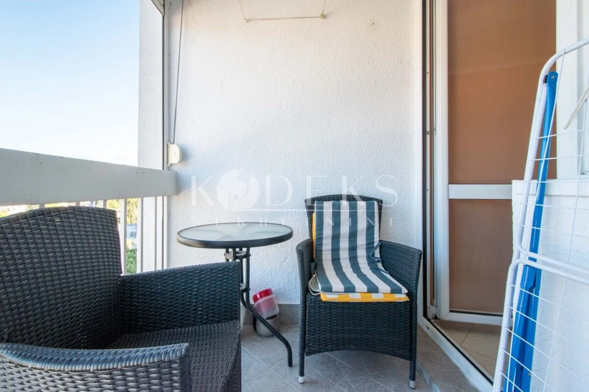 Manji balkon opremljen stolom, dvije fotelje i stalkom za sušenje veša.