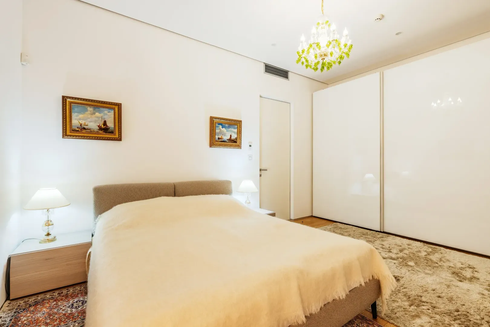 Prostrana spavaća soba sa bračnim krevetom, velikim plakarom i lusterom.