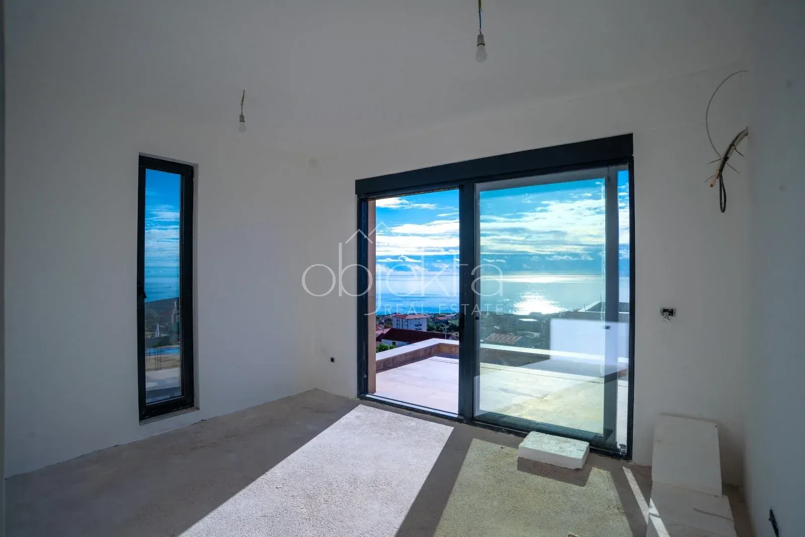Unfurnished room under construction with large windows and a sea view.