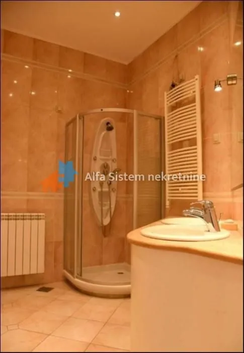 Tiled bathroom with a shower cabin and a washbasin.