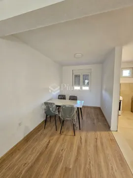 Dining area with a table and chairs in light tones facing a window. - image 3
