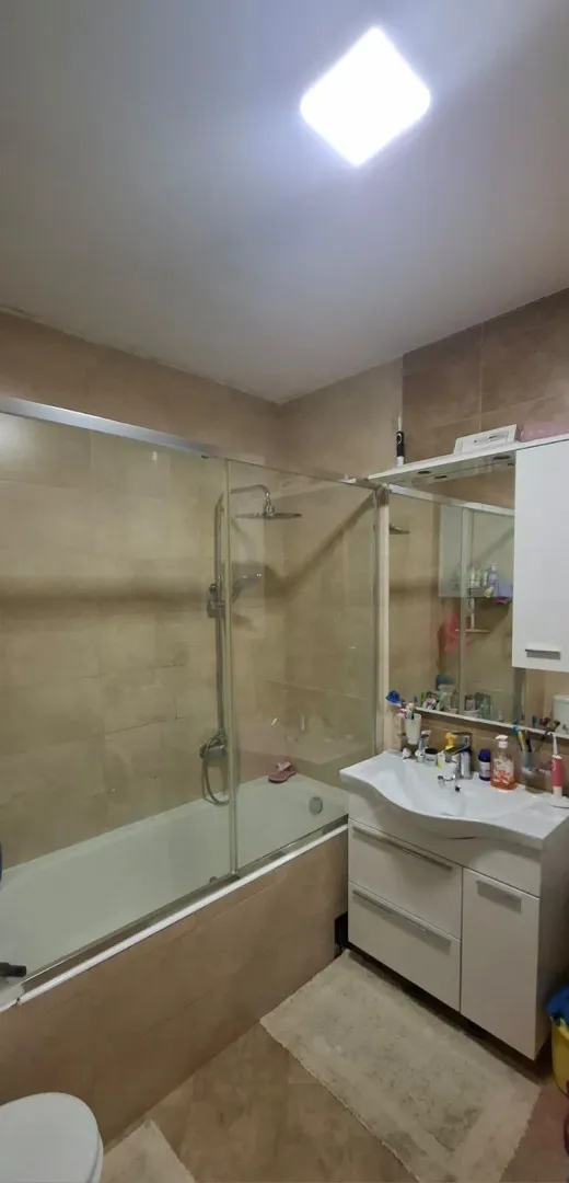 Kupatilo opremljeno tuš kabinom, umivaonikom i ormarićem sa ogledalom.