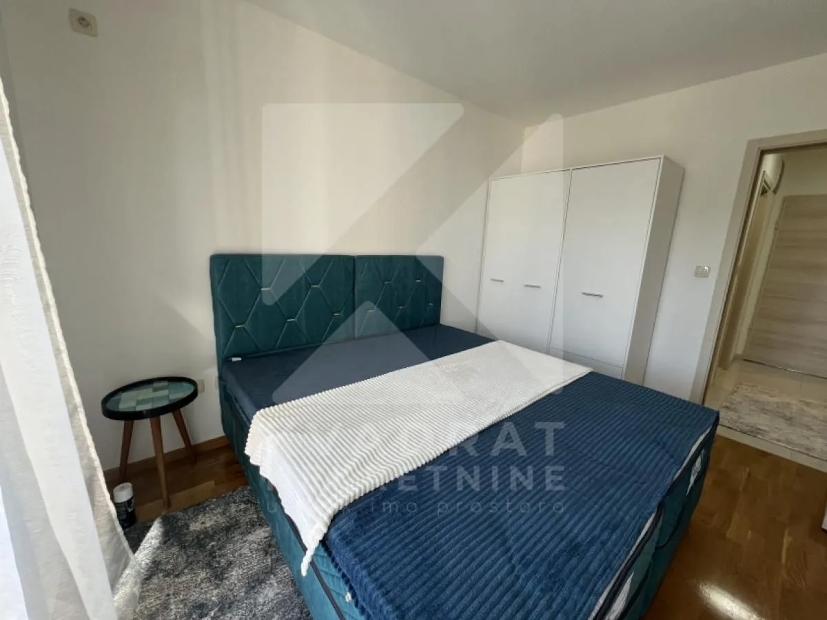 Furnished bedroom with a double bed and a wardrobe.