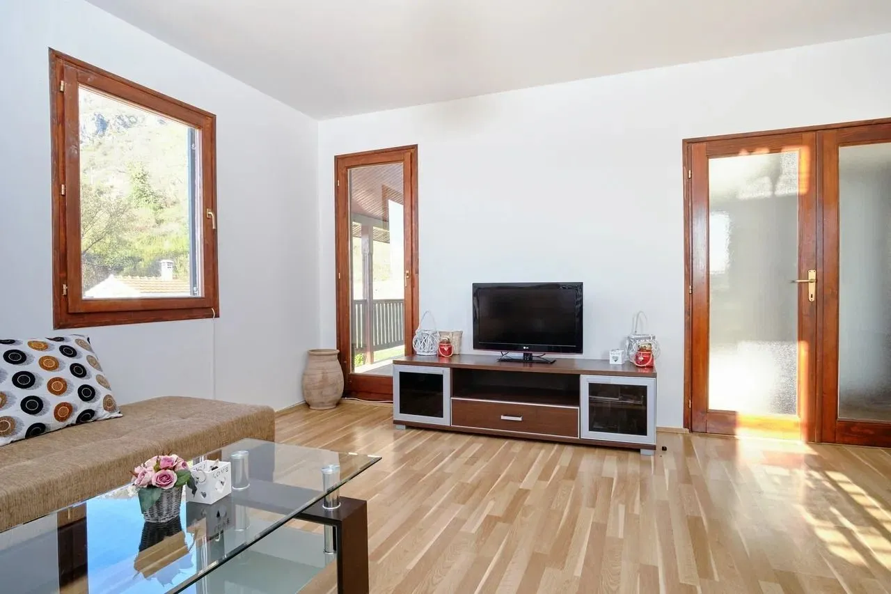Living room with a sofa, TV unit, and wooden flooring.