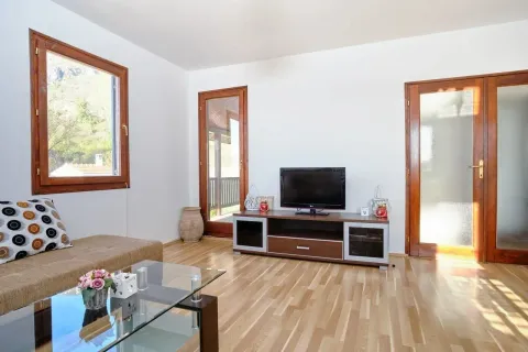 Living room with a sofa, TV unit, and wooden flooring. - image 11