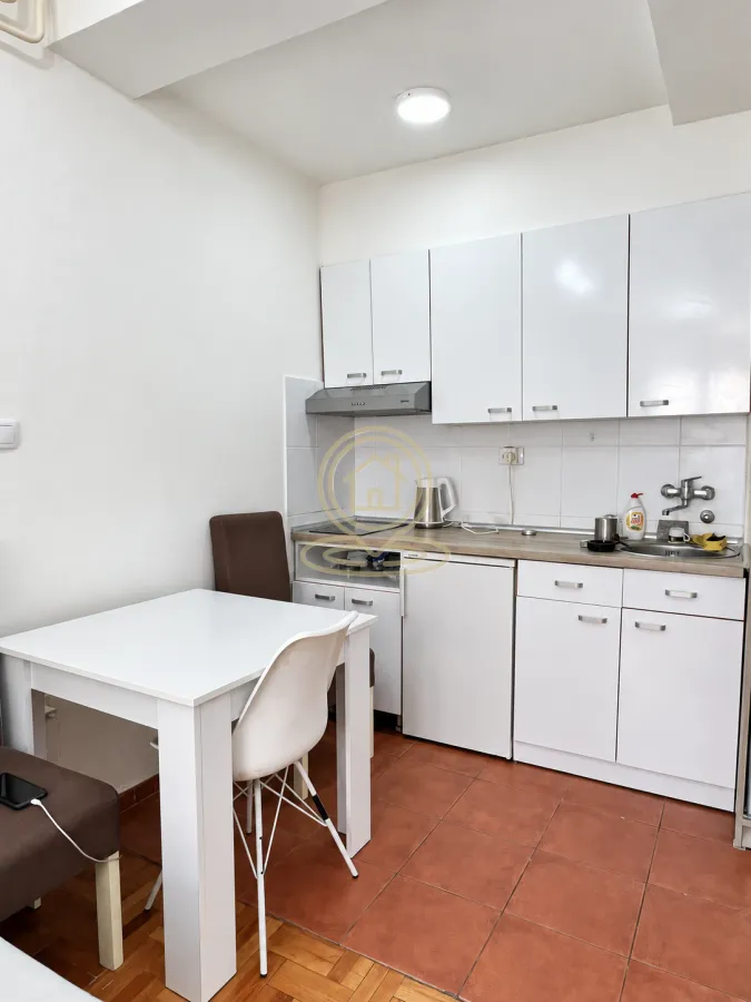 Small white kitchen with a dining table and chairs.