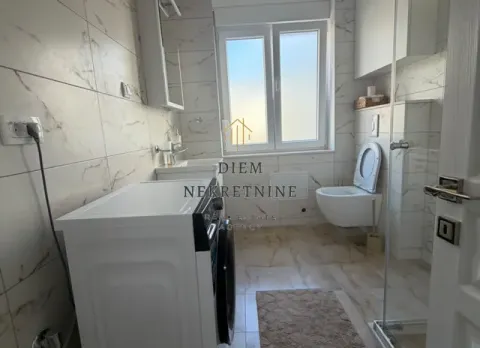 Modern bathroom with a washing machine, toilet, and walk-in shower. - image 11