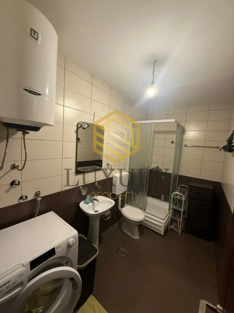 Manje kupatilo sa tuš kabinom, umivaonikom, WC šoljom i veš mašinom.