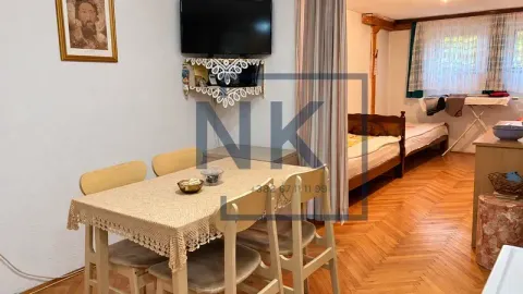 Dnevni boravak sa trpezarijskim stolom i krevetom u pozadini. - image 8