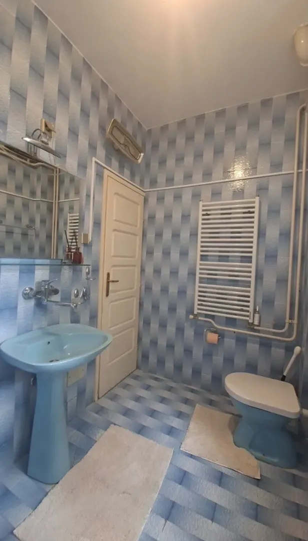 Manje kupatilo sa plavim sanitarijama i pločicama u tonovima plave boje.