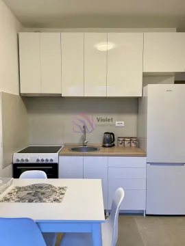 Small white kitchen with a stove, refrigerator, and dining table. - image 5